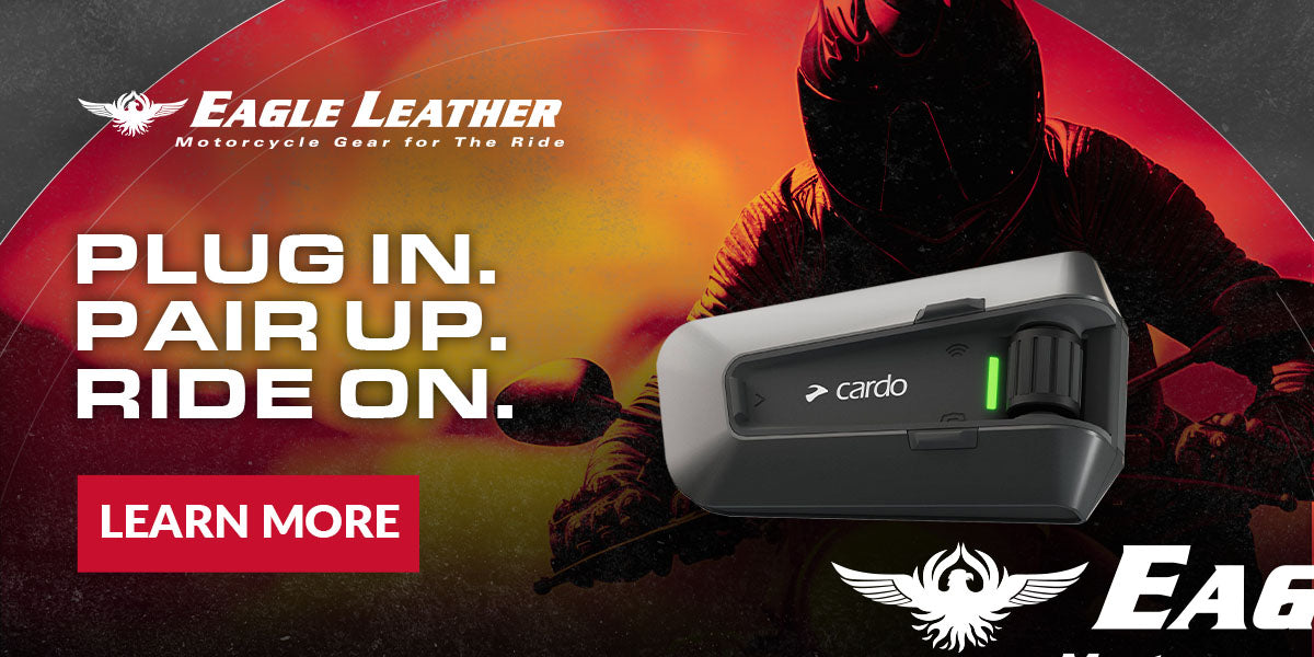 Eagle Leather banner with Cardo motorcycle communication device, tagline 'Plug In. Pair Up. Ride On.' Bold red and yellow background with motorcycle rider in helmet, Eagle Leather logo, and red Learn More button.