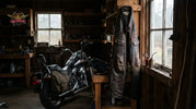 Well-maintained leather motorcycle chaps hanging in a Pacific Northwest garage near a cruiser motorcycle