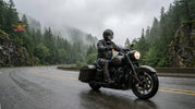 Cruiser rider wearing motorcycle chaps riding through wet Pacific Northwest highway