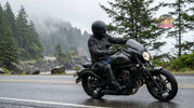 Motorcycle rider wearing leather chaps for wind and cold weather protection while riding a cruiser in the Pacific Northwest