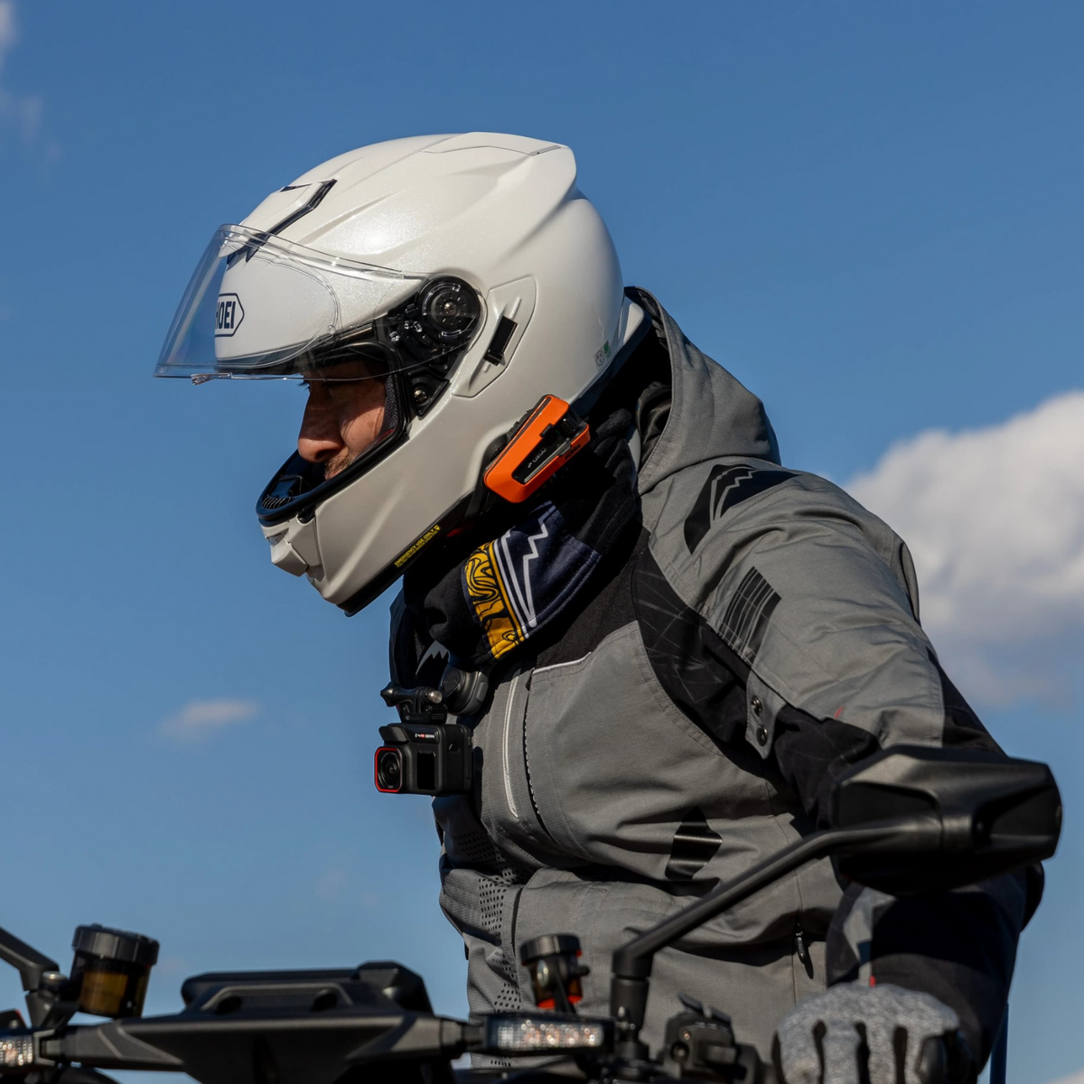 Cardo PACKTALK EDGE KTM orange communicator mounted on a touring rider's helmet