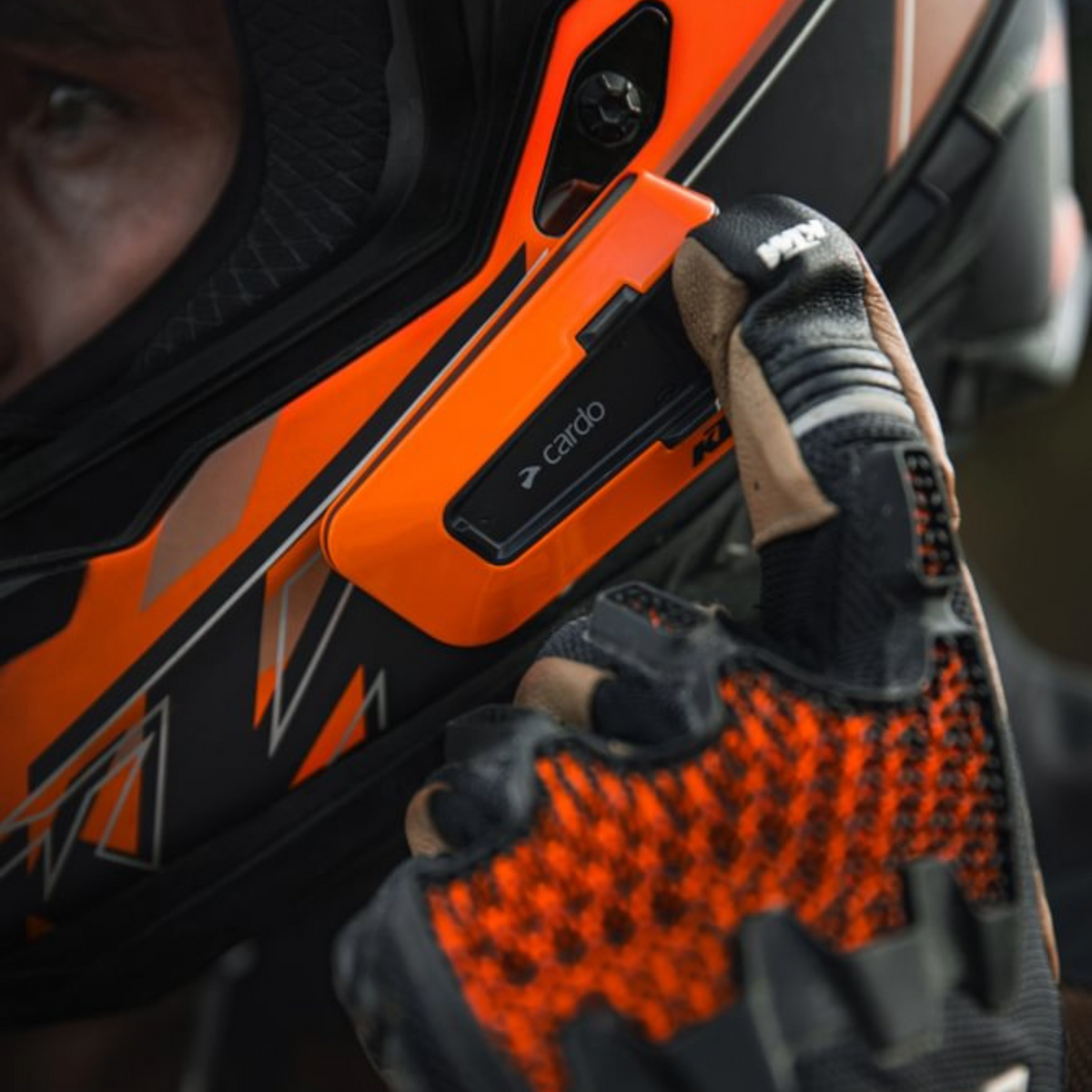 Cardo PACKTALK EDGE KTM orange communicator controls used with a gloved hand