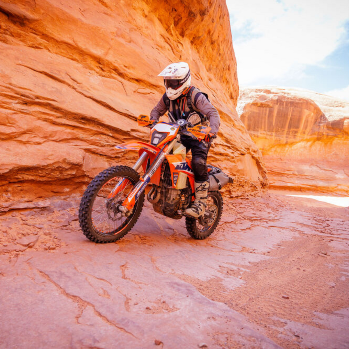 Cardo PACKTALK EDGE KTM orange communicator on an off-road rider in a canyon