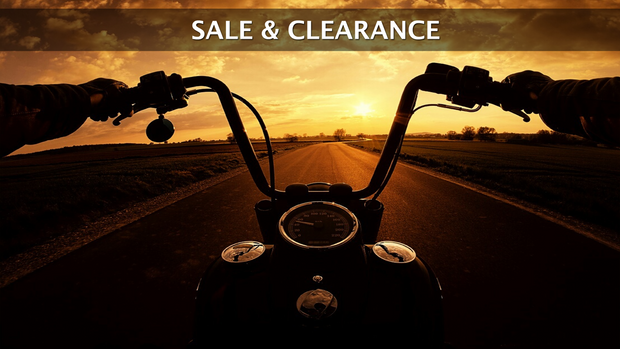 View from a motorcycle rider's perspective looking down an empty road at sunset. The image features the text 'Sale & Clearance' across the top.