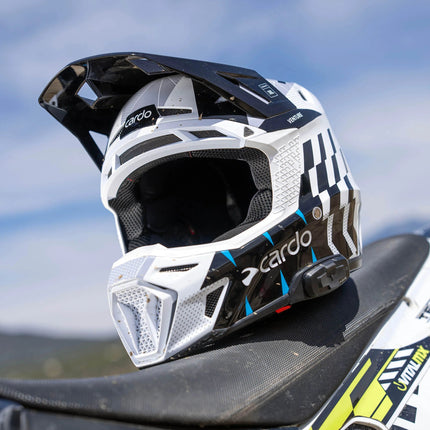 Cardo VENTURE helmet resting on a dirt bike