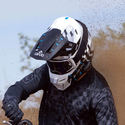 Off-road rider wearing the Cardo VENTURE helmet in dusty conditions