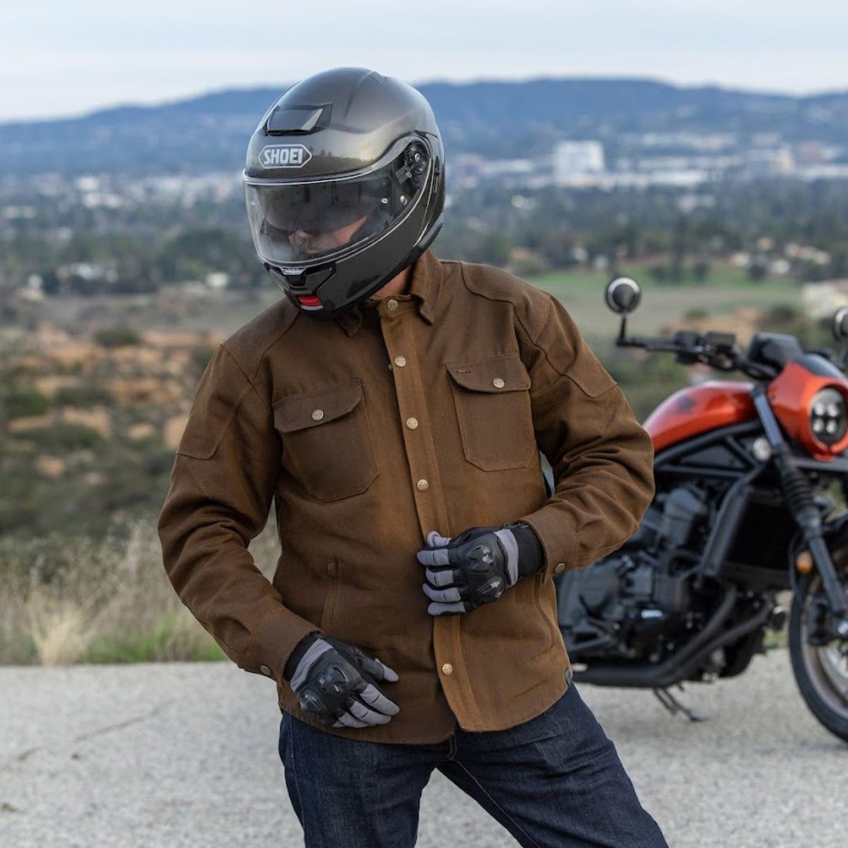 Cortech Rambler wax cotton riding jacket in Brown, rider wearing jacket beside a motorcycle