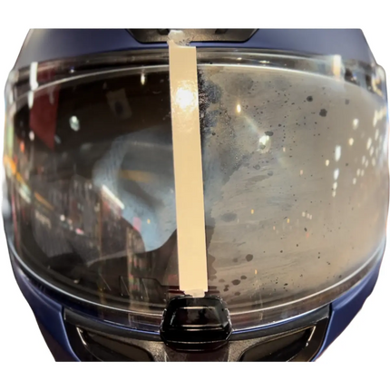 Motorcycle helmet visor showing a clear left side treated with Eagle Leather Anti-Fog Spray and a fogged right side untreated, demonstrating the product’s effectiveness.