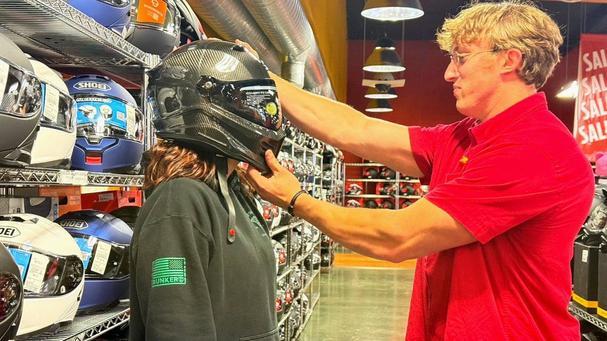 Eagle Leather staff member fitting a full-face motorcycle helmet on a customer in the Lakewood, WA store