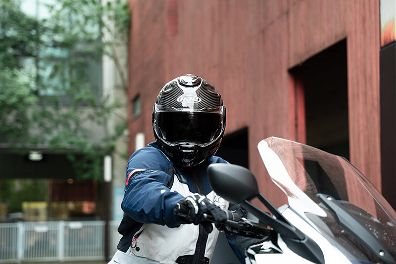 Rider wearing the HJC F100 Carbon helmet on a touring motorcycle