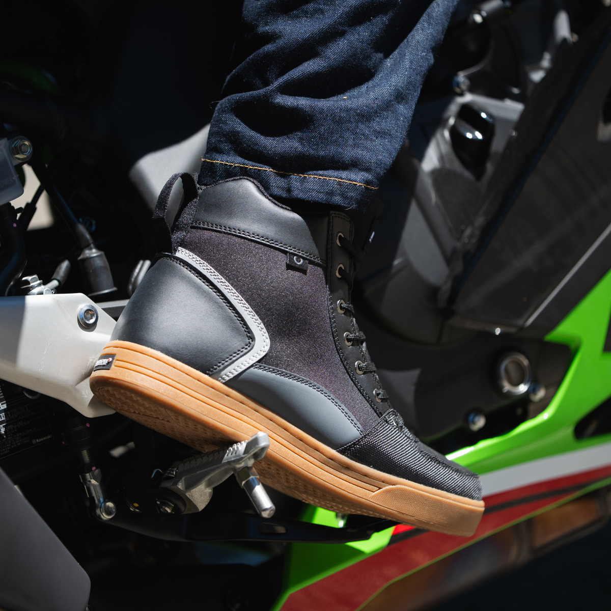 NORU Men’s Tori Boot in black with gum sole positioned on a motorcycle footpeg
