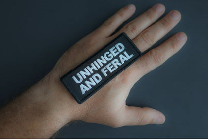Unhinged and Feral patch shown in hand for size reference