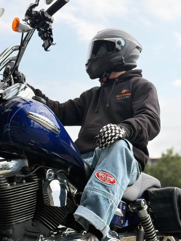 Person wearing a helmet and gloves sitting on a motorcycle with visible branding.