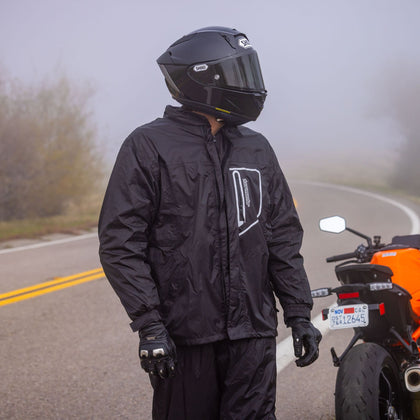 Tourmaster Defender Two-Piece Rainsuit in Black - full suit worn beside motorcycle