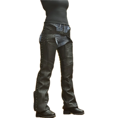 Women's black leather motorcycle chaps with lace-up sides, silver grommets, and adjustable front belt, worn over denim jeans and paired with black boots.