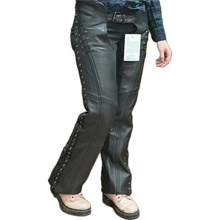 Woman wearing black leather lace-up motorcycle chaps over jeans, shown from a different angle to highlight the fit, detailing, and side lacing.